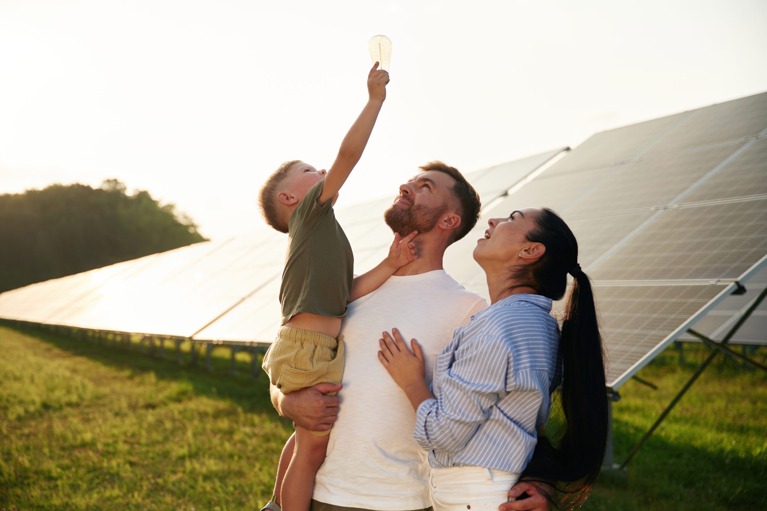 Light Bulb Hand Father Mother Little Son Are Outdoors Near Solar Panels Scaled